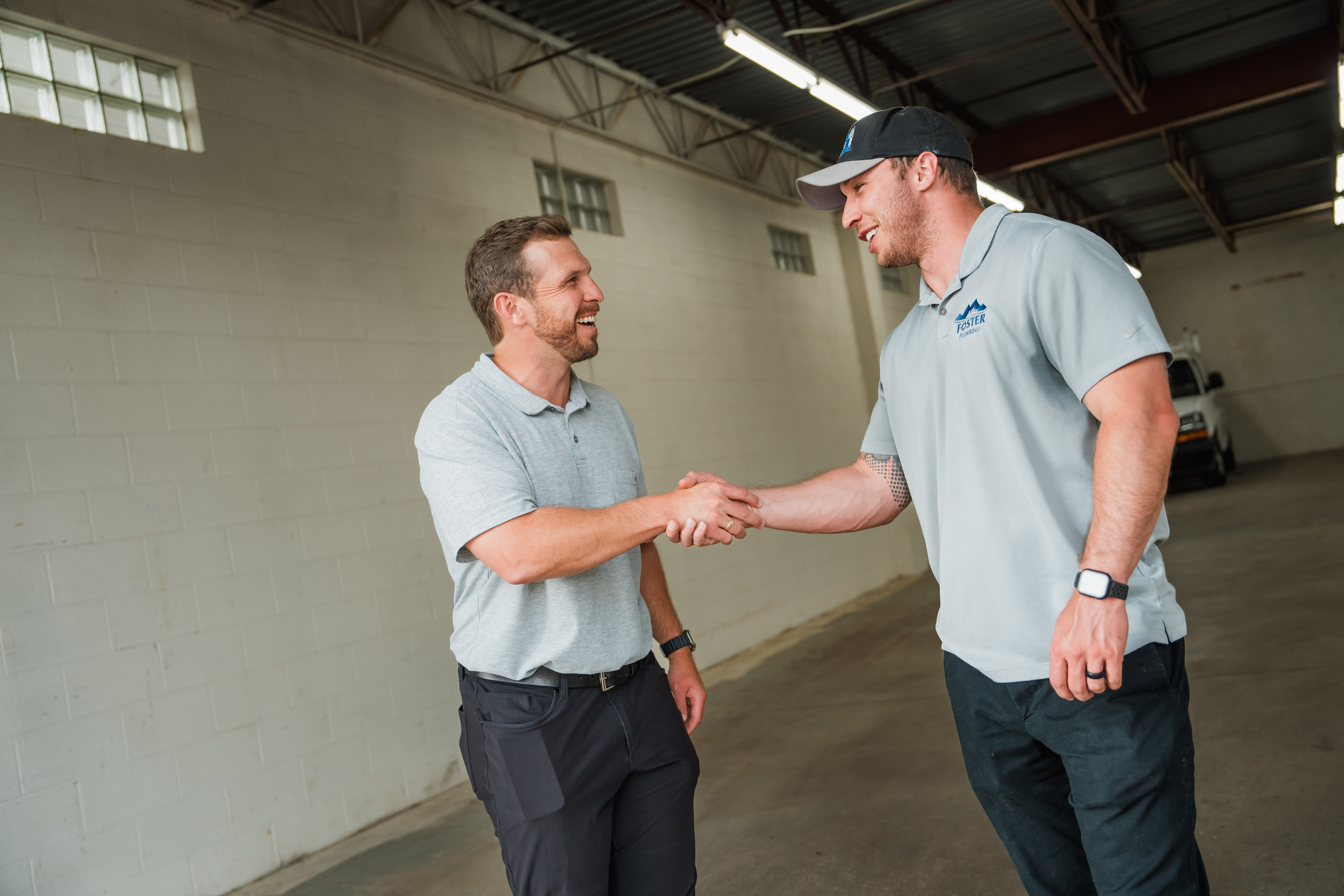 SAMG principal shaking hands with a Foster Plumbing tenant inside a Colorado small-bay industrial unit